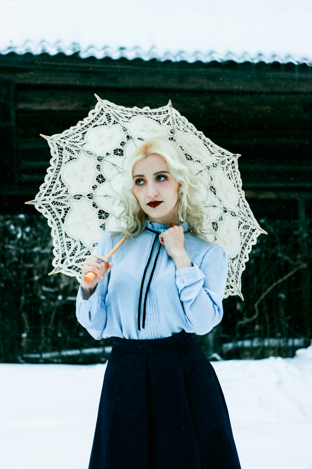 woman in blue dress shirt and blue skirt holding umbrella