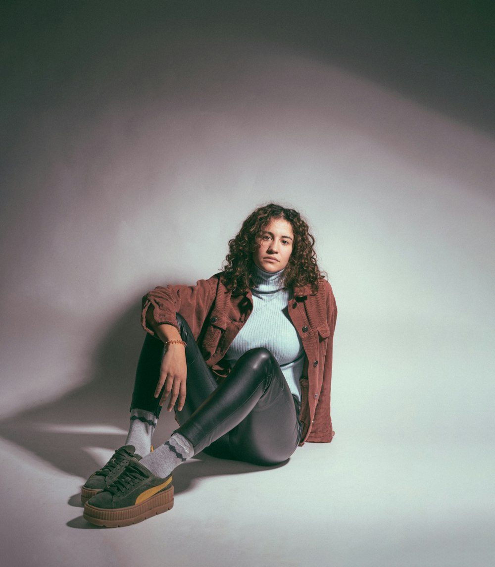 woman wearing brown jacket leaning on wall