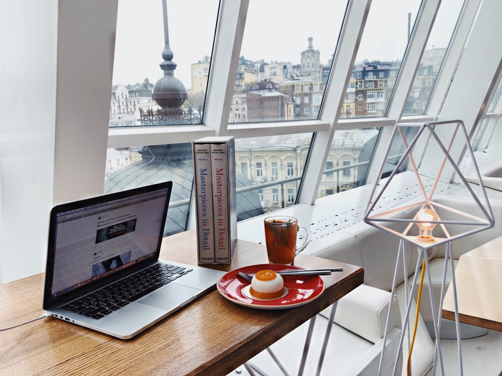 MacBook Pro near food on red plate on brown wooden table