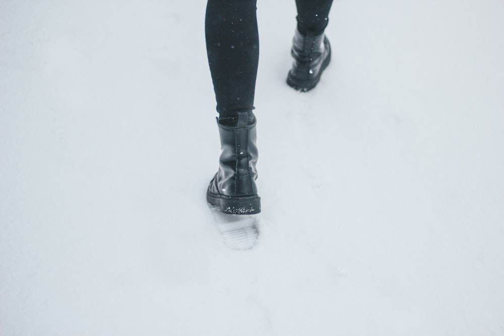 Persona con botas de cuero negras pisando la nieve