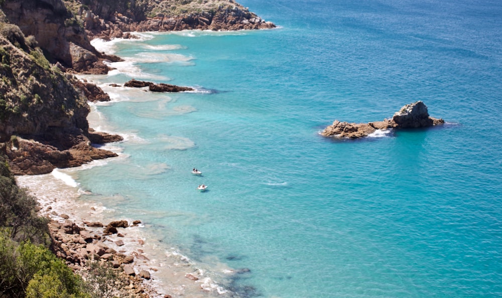 boats on calm sea near mountain