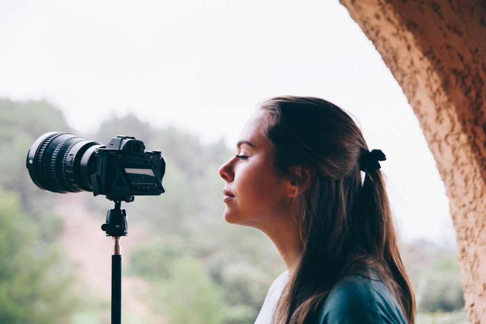 woman looking at black DSLR camera