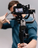 man holding black DSLR camera with stabilizer