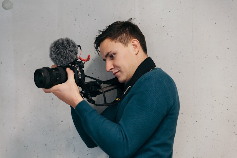 man in blue sweater using DSLR camera