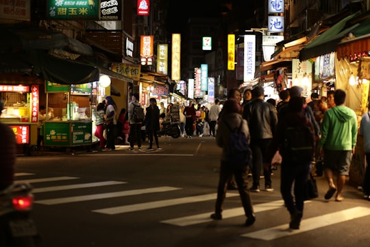 A lively night market scene with colorful lights and smiling families enjoying food stalls.