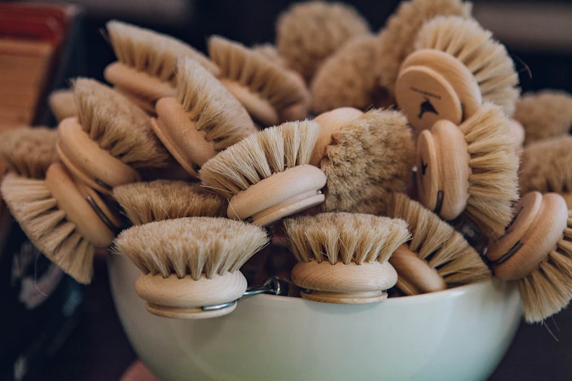 Natural wooden bath brushes arranged neatly on a cream-toned surface with soft shadows.