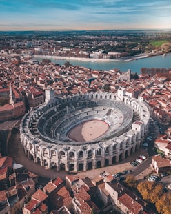 gray stadium surrounded by buildings near body of water