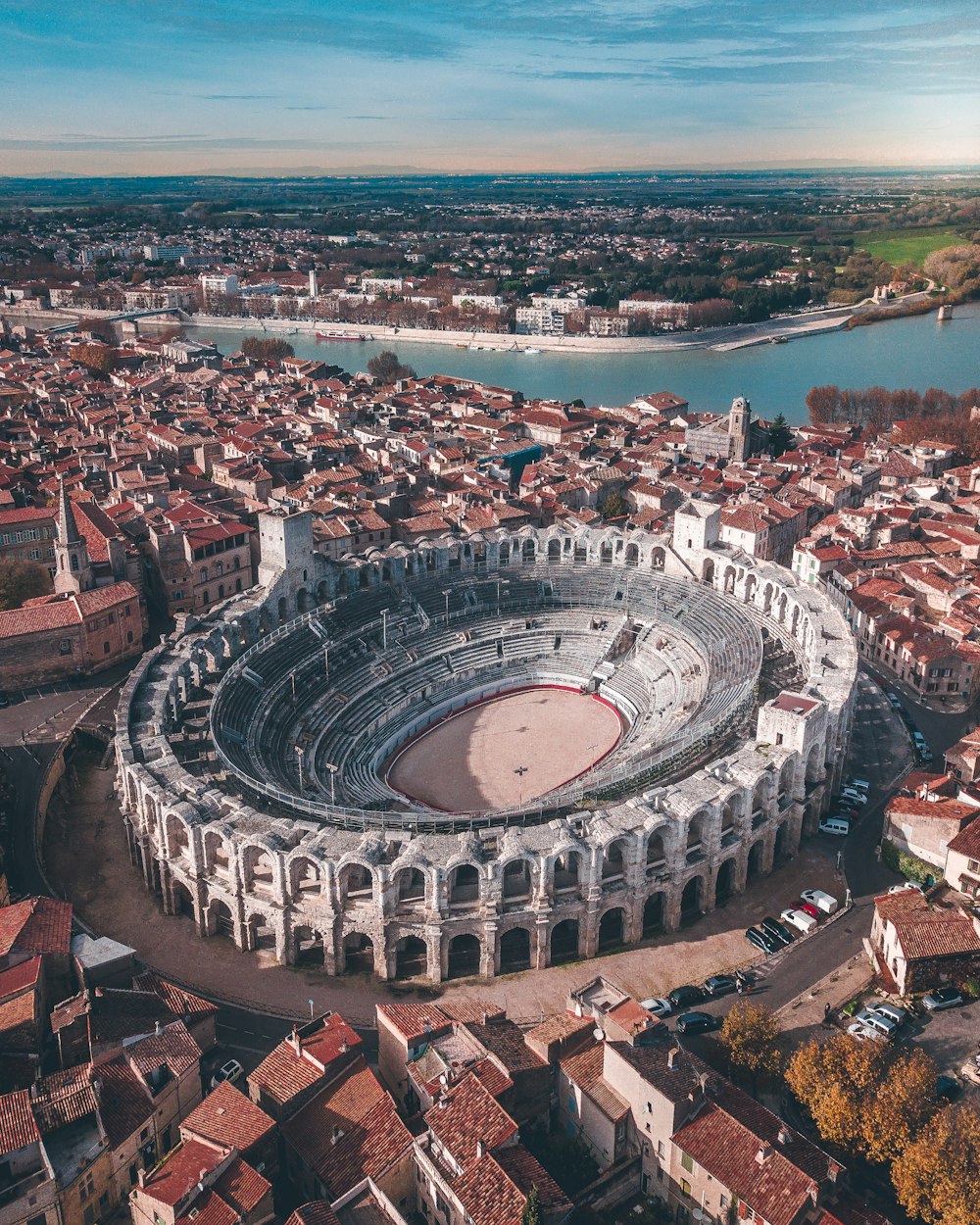 gray stadium surrounded by buildings near body of water