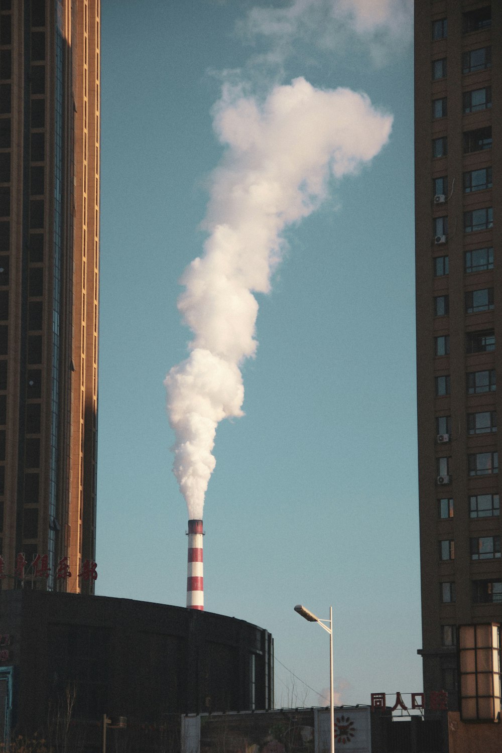 Rot-weißes Metallrohr, das tagsüber weißes Gas in die Luft bläst