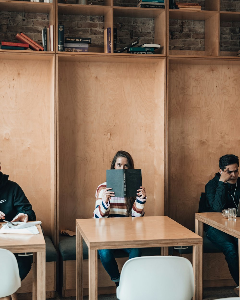 woman reading book near square brown wooden table