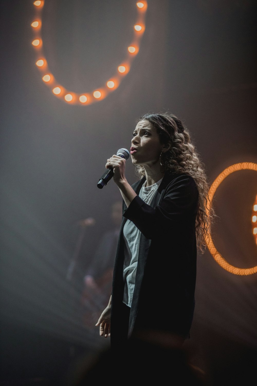 singing woman in black cardigan holding microphone