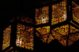 Close-up of a glowing Moroccan metal lantern casting intricate shadows.