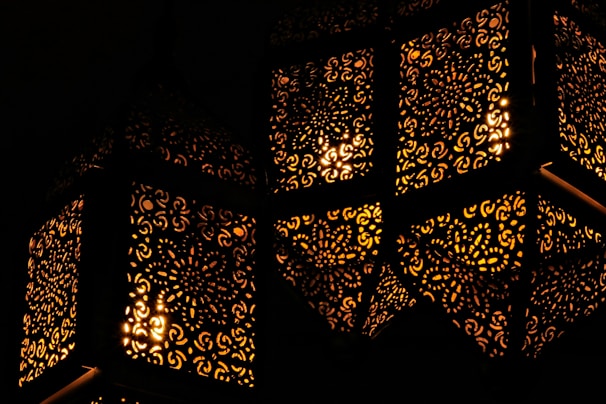 Close-up of a delicate handcrafted metal lantern with intricate cut-out patterns casting warm light.