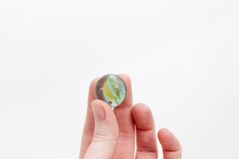 person holding yellow and green marble toy