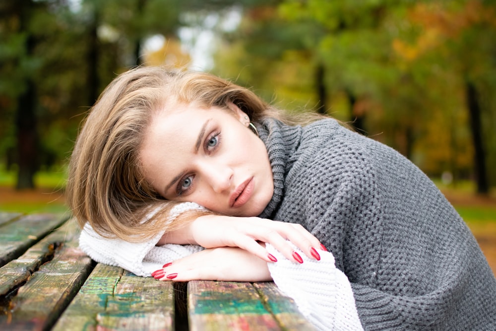 woman lying his head on brown wooden table during daytime