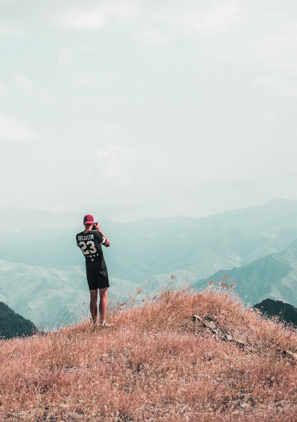 man wearing black shirt standing on cliff