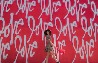 woman wearing brown-and-black mini dress standing near graffiti