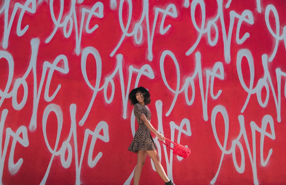 woman wearing brown-and-black mini dress standing near graffiti