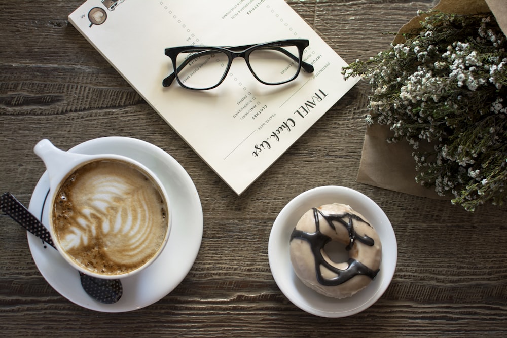 flatlay photo of latte with leaf art and doughnut