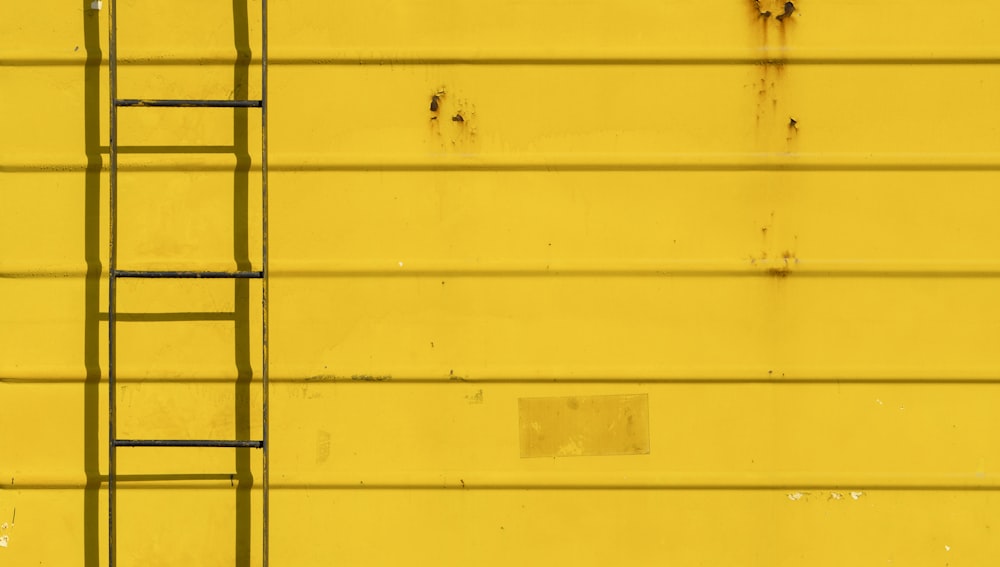 black metal ladder on yellow wall
