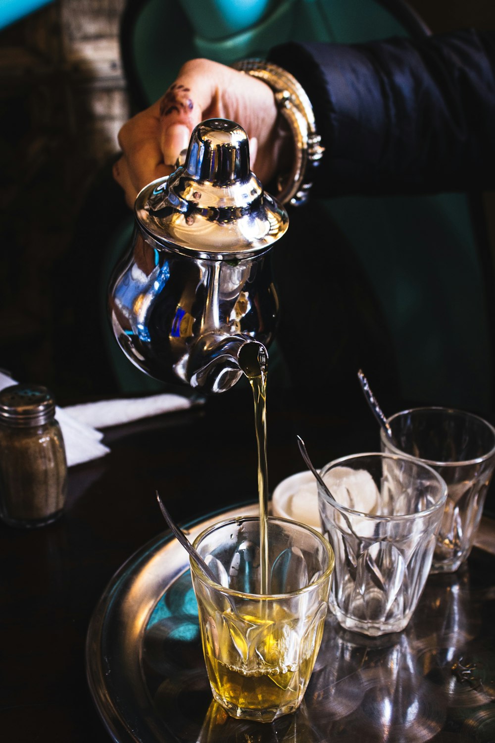 person pouring tea on clear glass cup