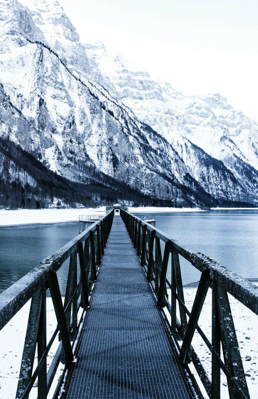 black metal bridge near snow covered mountains
