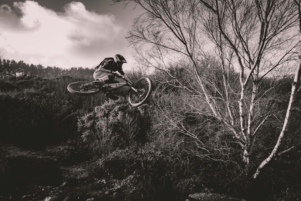 grayscale photo of man riding bicycle