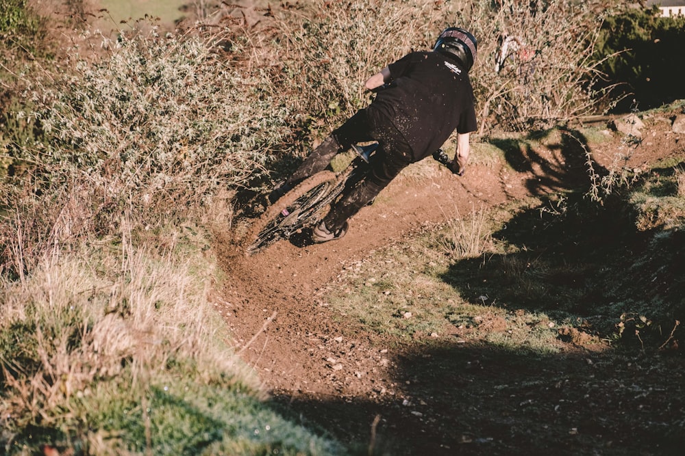 black short coat medium dog running on brown dirt road during daytime