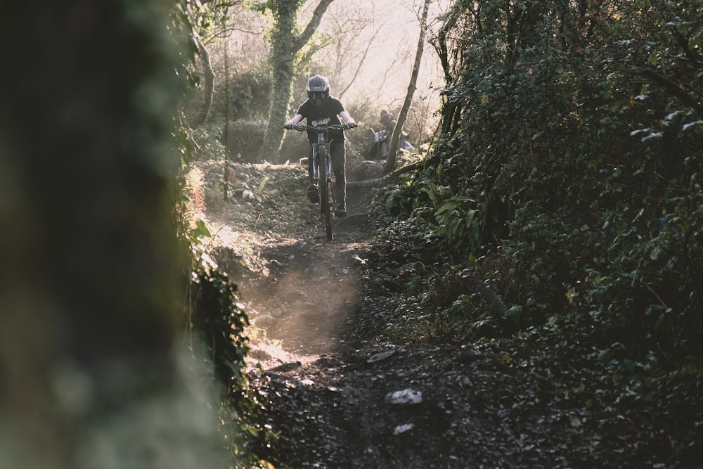 man in black jacket riding bicycle on dirt road during daytime