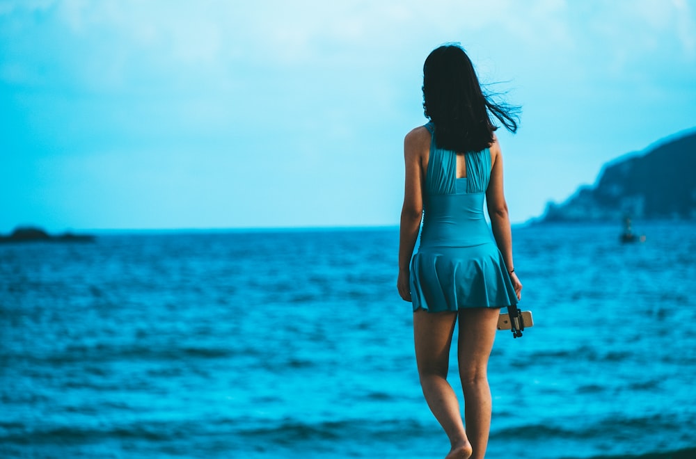 woman in blue midi dress standing near sea