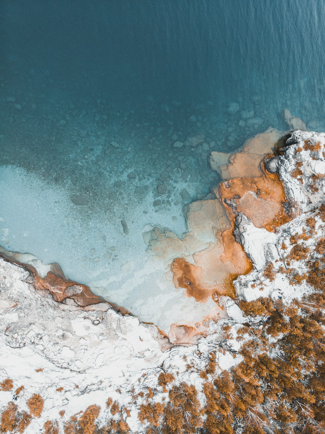 aerial photography of snow-covered cliff near body of water during daytime