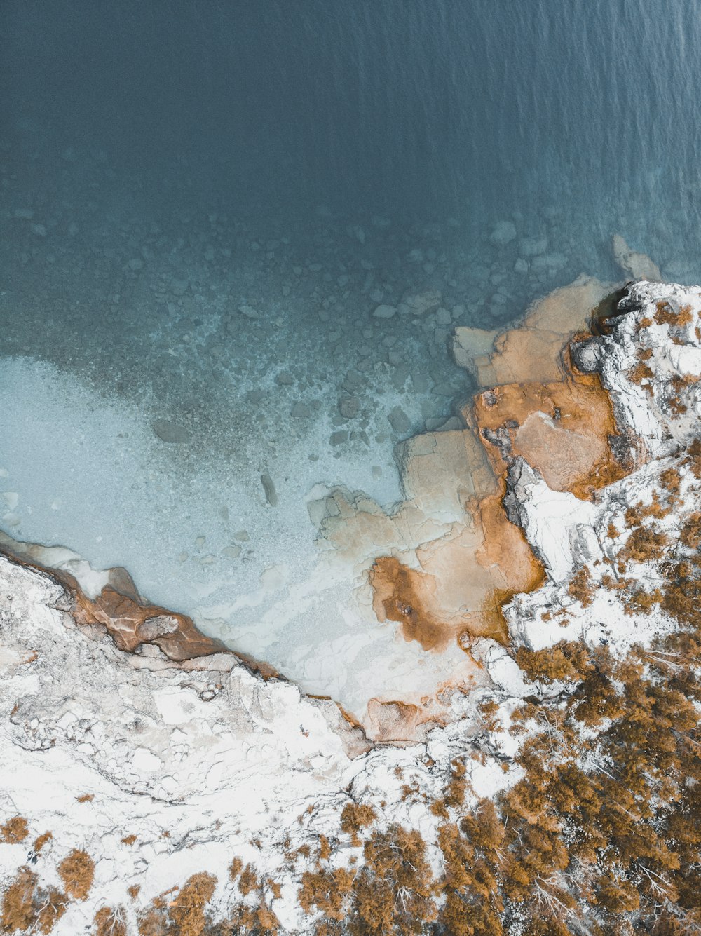 aerial photography of snow-covered cliff near body of water during daytime