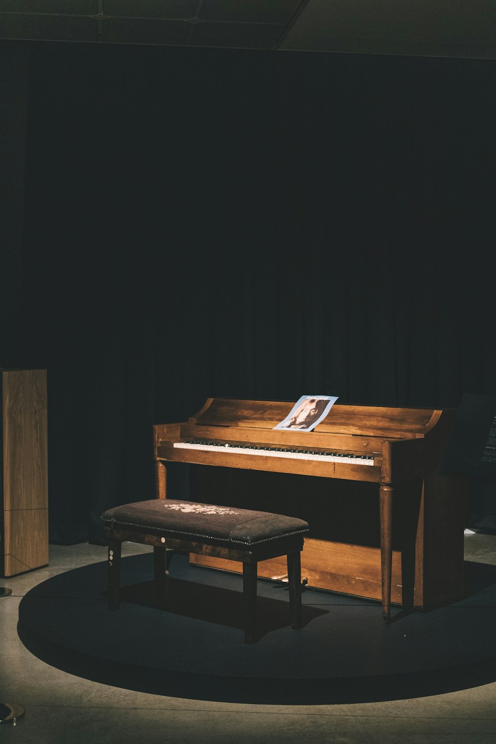 brown wooden upright piano with ottoman bench and light turned-on