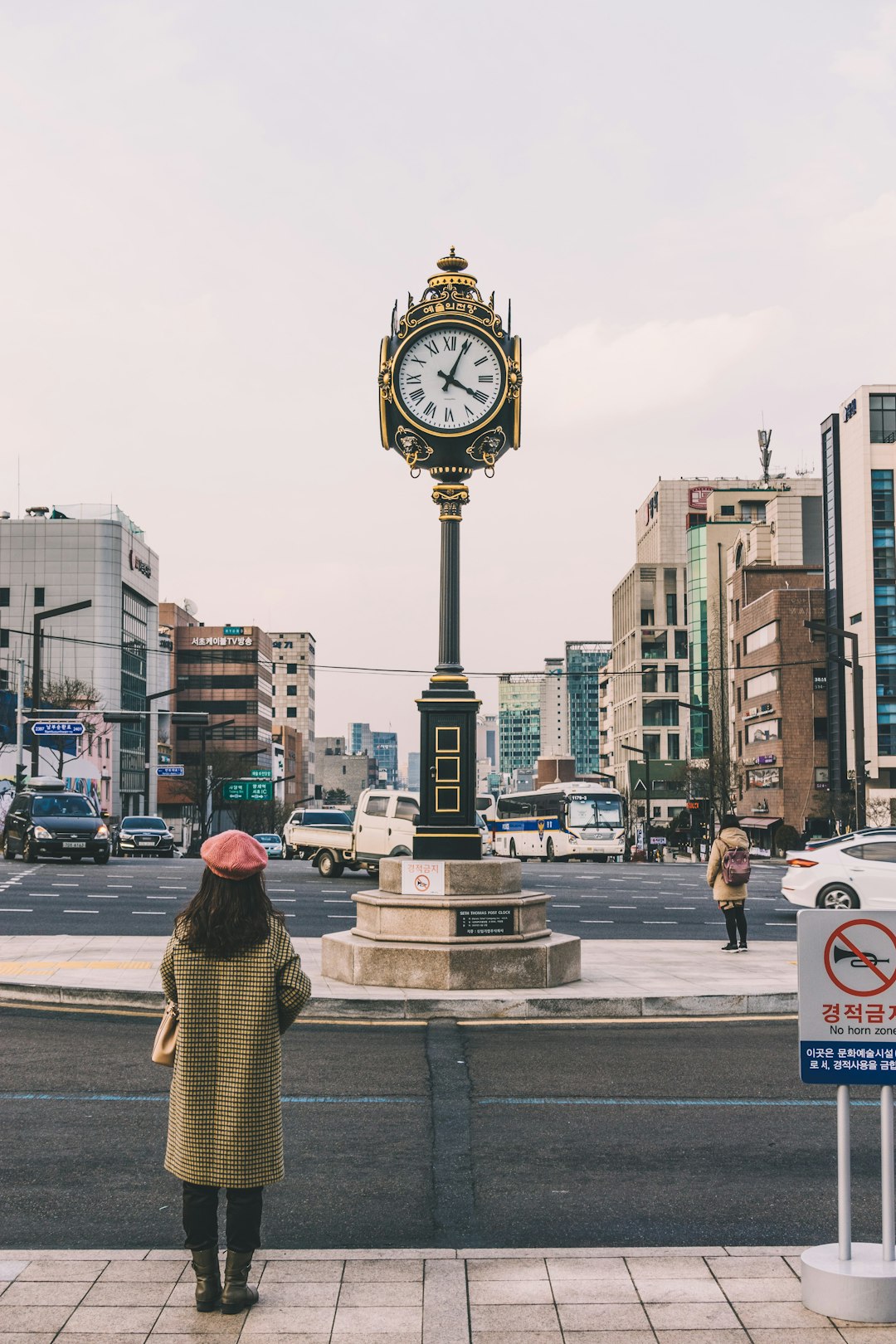 woman standing on street facing clock