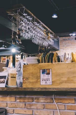 Hanging wine glass racks filled with sparkling glasses above a cozy home bar setup.