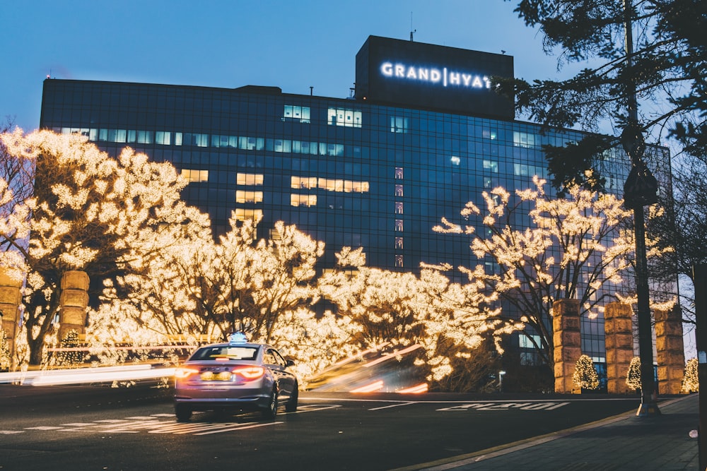 sedan running near Grand Hyay building during dusk