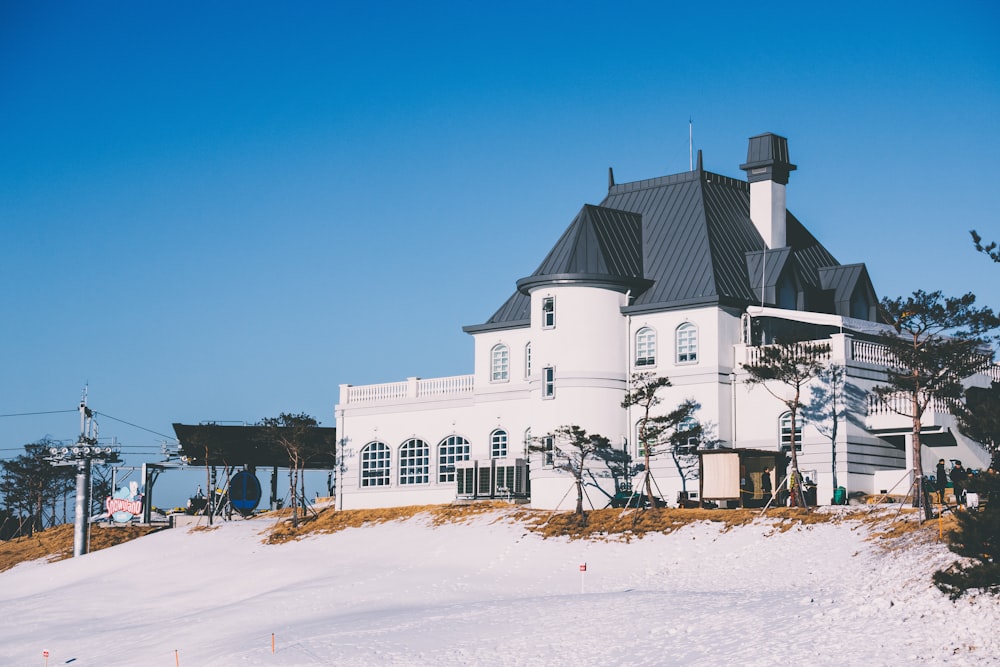 white and grey concrete house surrounded by snow covered field under blue sky