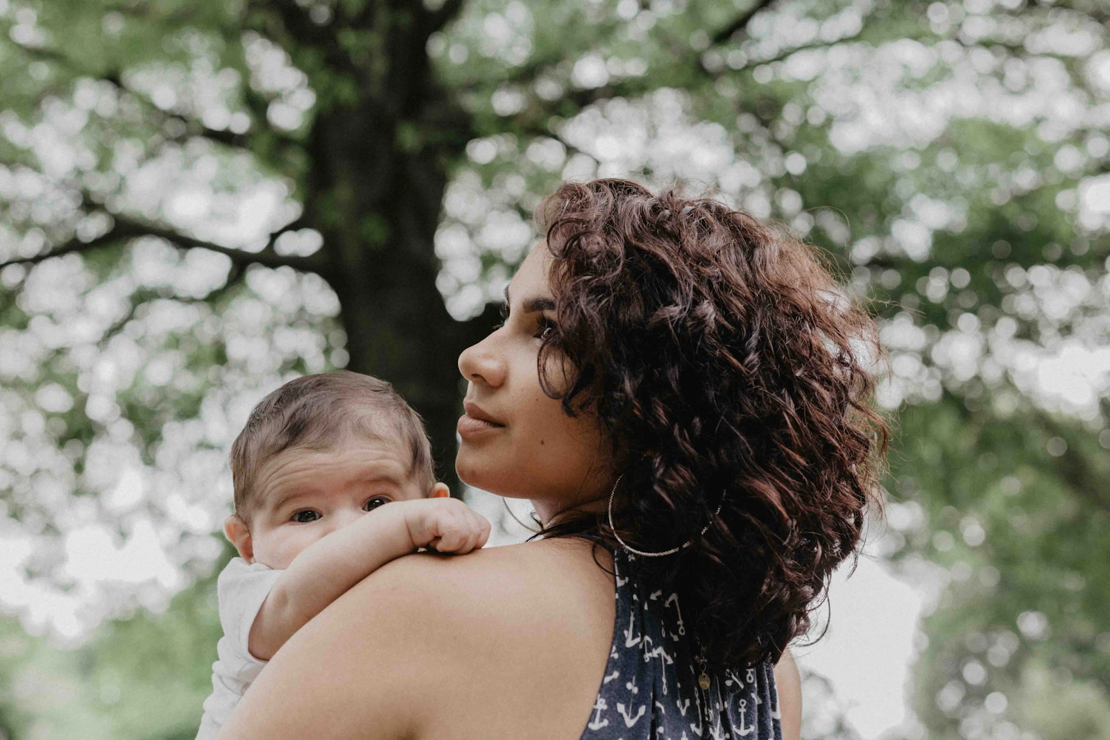 A mother carries her newborn close in a tender postpartum moment, the kind of bonding our Fourth Trimester Plan helps families protect and prepare for.