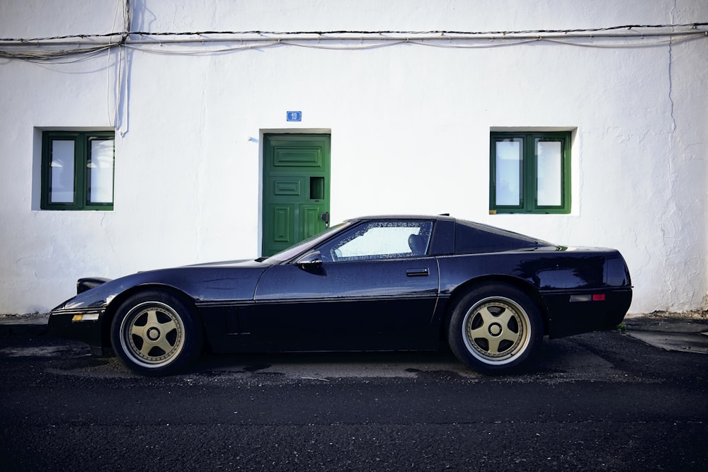 classic black coupe parked outside white building