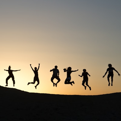 six silhouette of people jumping during sunrise