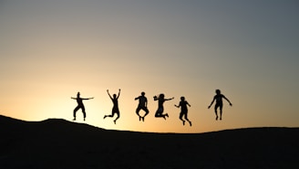 six silhouette of people jumping during sunrise