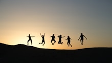 six silhouette of people jumping during sunrise