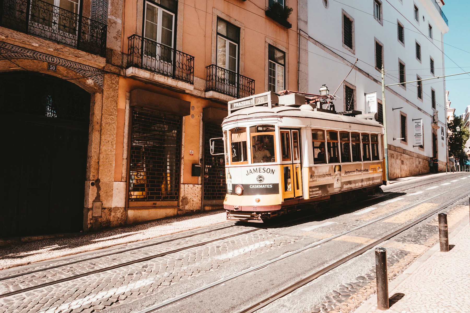A vintage white and yellow tram climbing a steep cobbled street between old buildings
