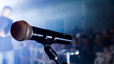 Close-up of a journalist reporting live with a microphone amid a busy backdrop.