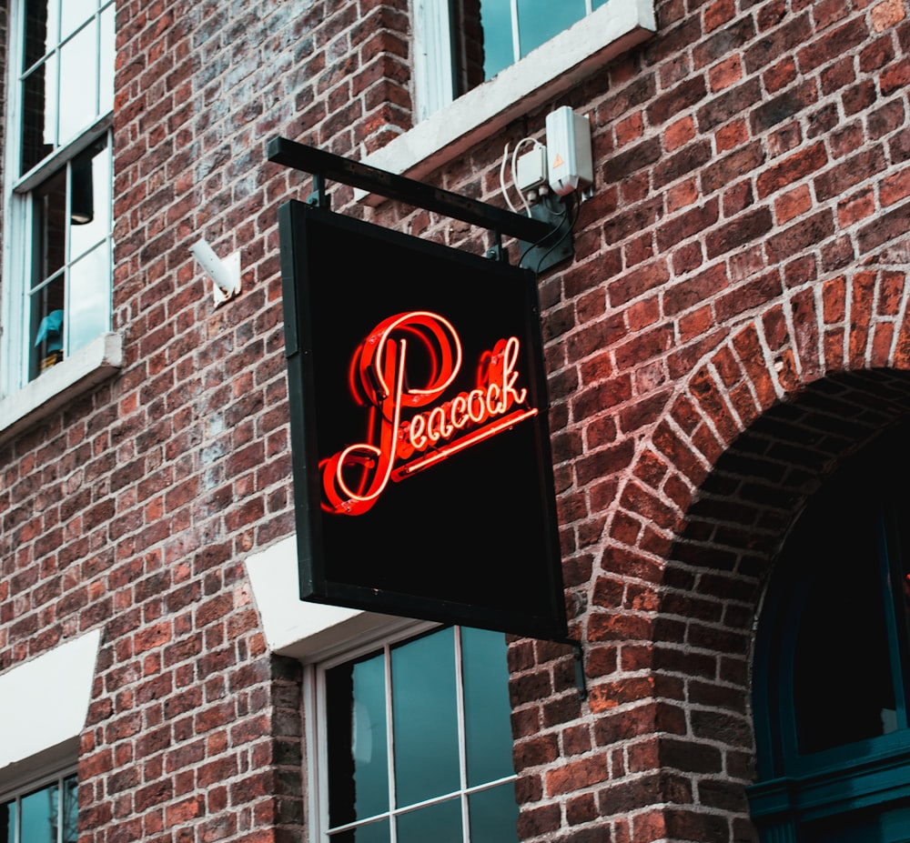 Peacock signage hung on brick wall