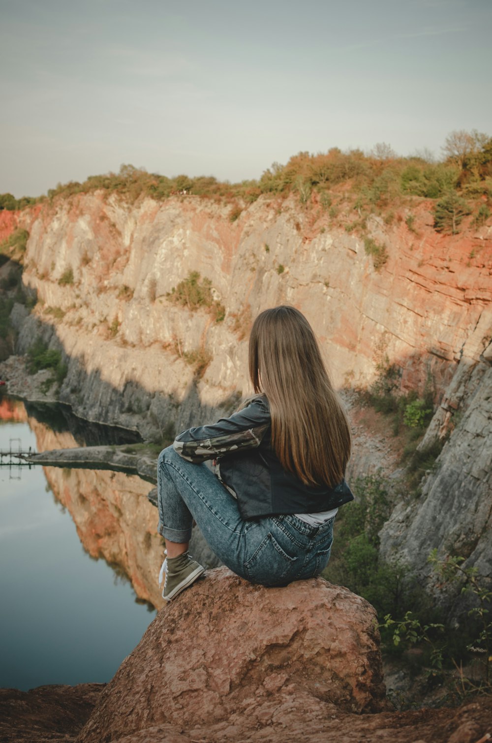 person sitting on the edge of cliff during daytime
