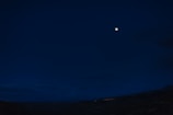 A serene night sky with a bright full moon illuminating a landscape.
