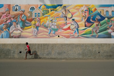 boy running beside multicolored wall painting during daytime cabo verde google meet background