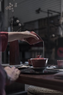 Barista pouring tea into a ceramic cup in a calm setting.