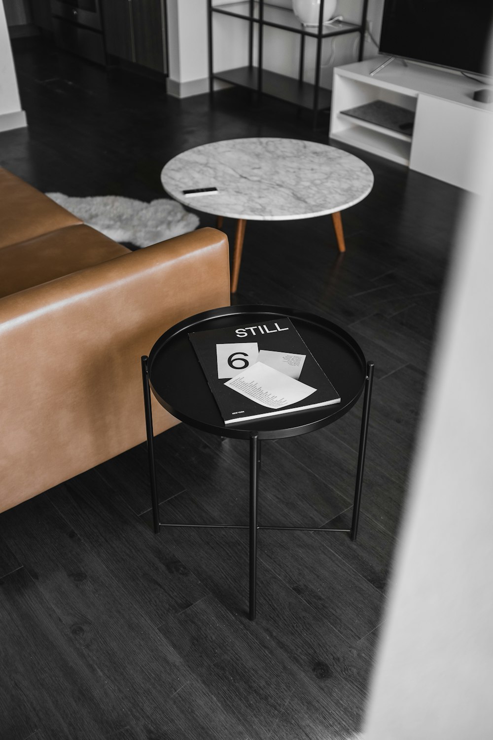 round white and black wooden tables beside brown leather sofa